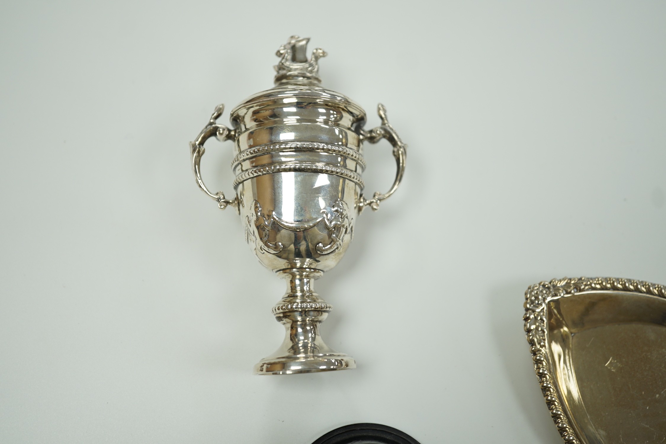 A miniature George V Scottish silver lidded trophy cup, on stand, Edinburgh, 1913, overall 14cm and a George V silver navette shaped dish.